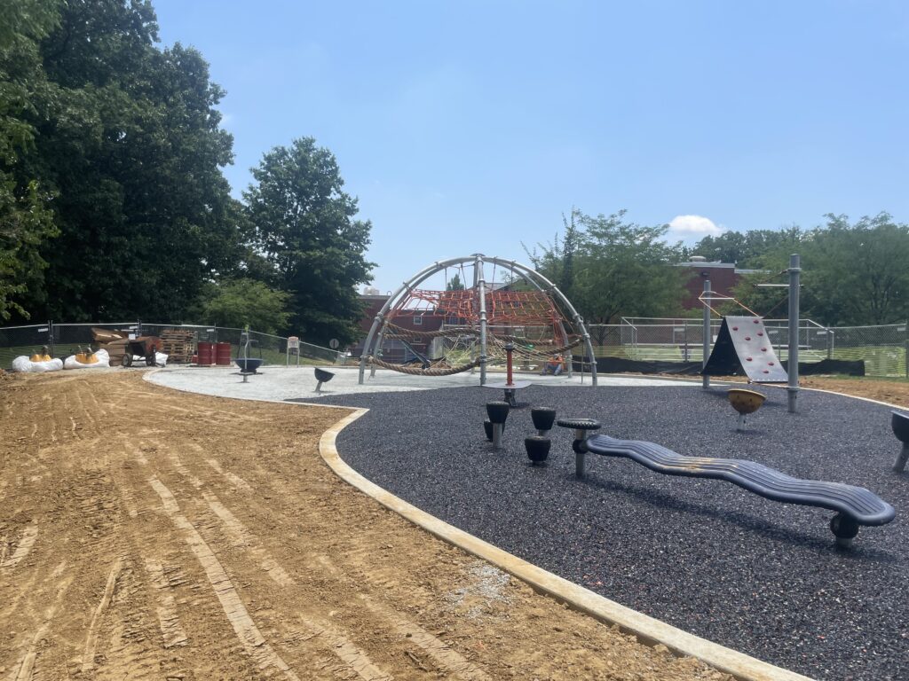 A photo of the playground towards the climbing structure - the base rubber mat is closer to the viewer and the compacted crushed stone aggregate further away at the Anne Beers Elementary School playground in Washington, D.C.