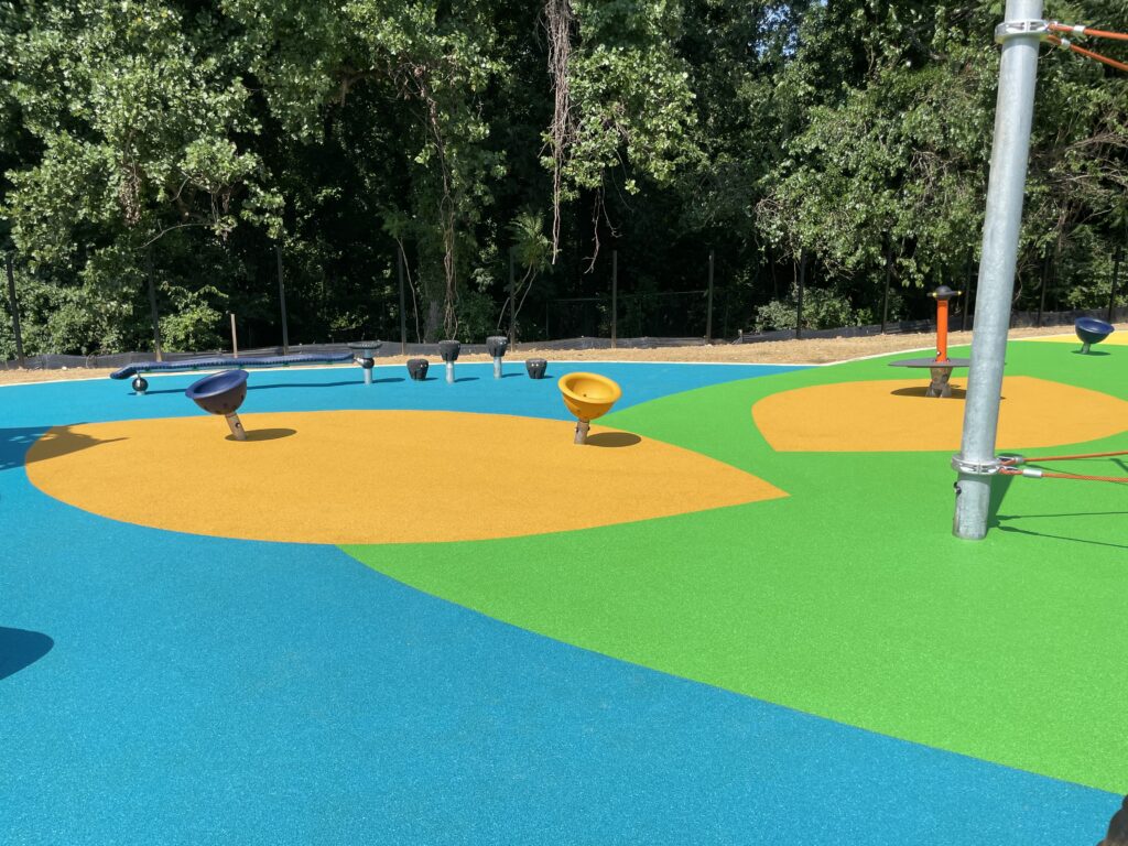 Custom Park Surfacing - Anne Beers - second stage - playground with green, yellow and blue poured rubber surfaces, completed project in a sunny picture.