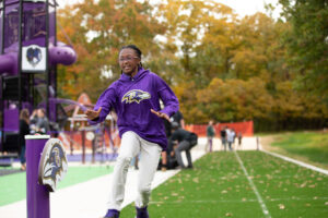 Kid running on a playground in a Baltimore ravens Hoodie