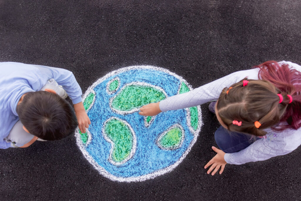 Kids on a playground drawing a globe with chalk