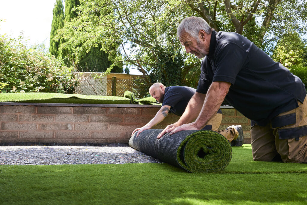 Rolling out second roll artificial grass