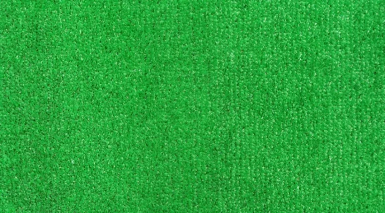 Close-up view of bright green artificial turf with short fiber strands and a textured surface (synthetic grass)